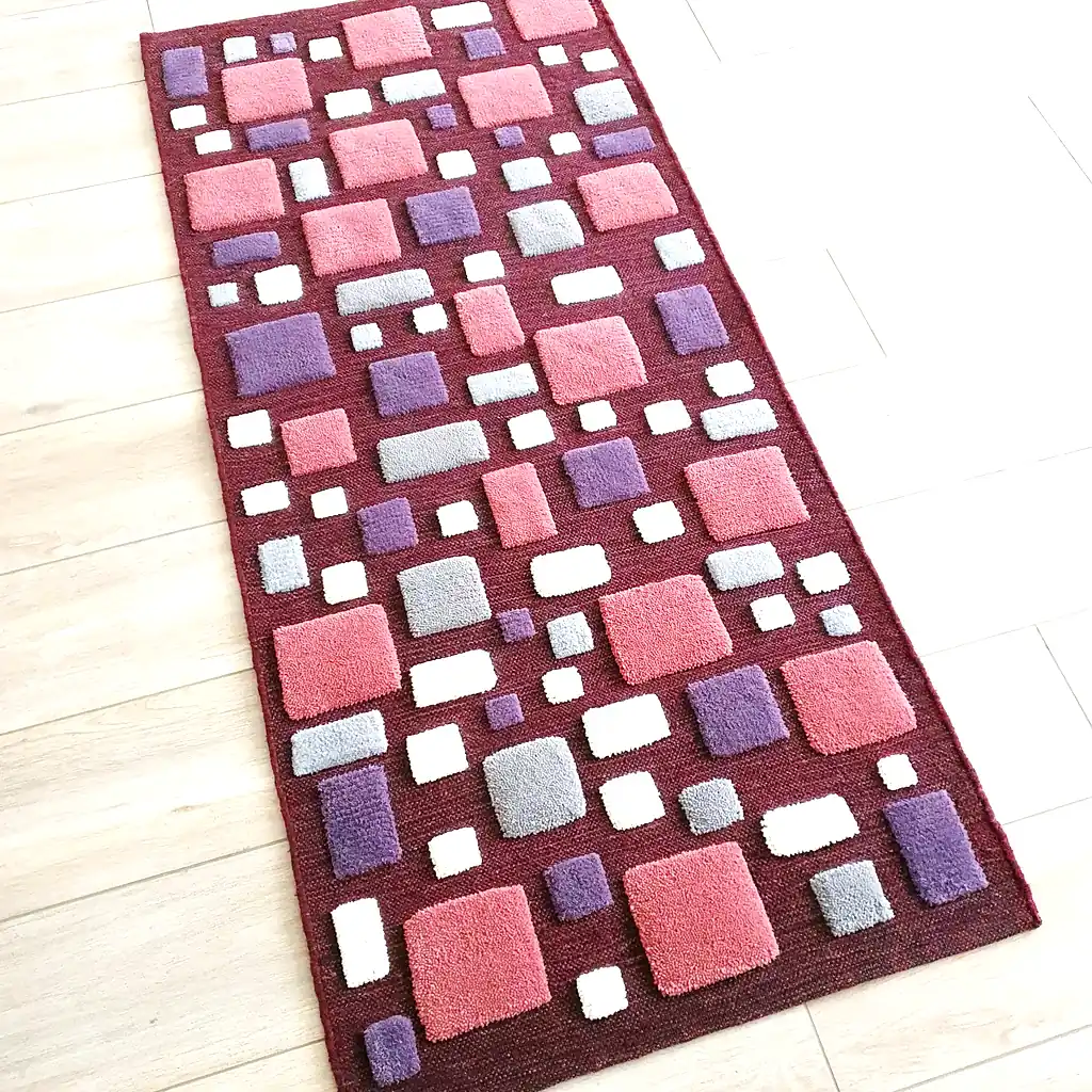 Handwoven wool area rug with 3D geometric texture in burgundy, pink, and lilac. Unique artisan floor decor by Modern Wool Style for modern interiors.