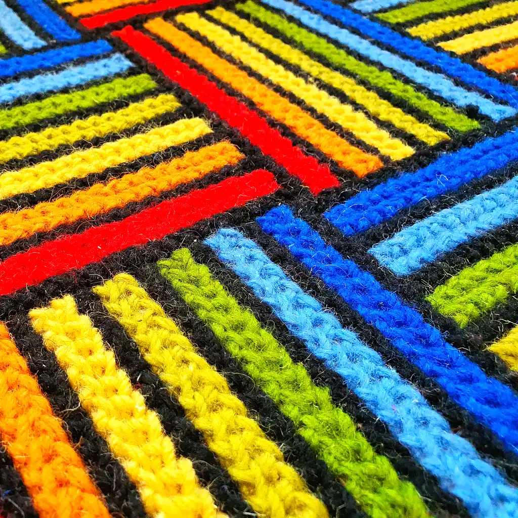 Detailed texture of thick wool yarn embroidered on a natural jute base.