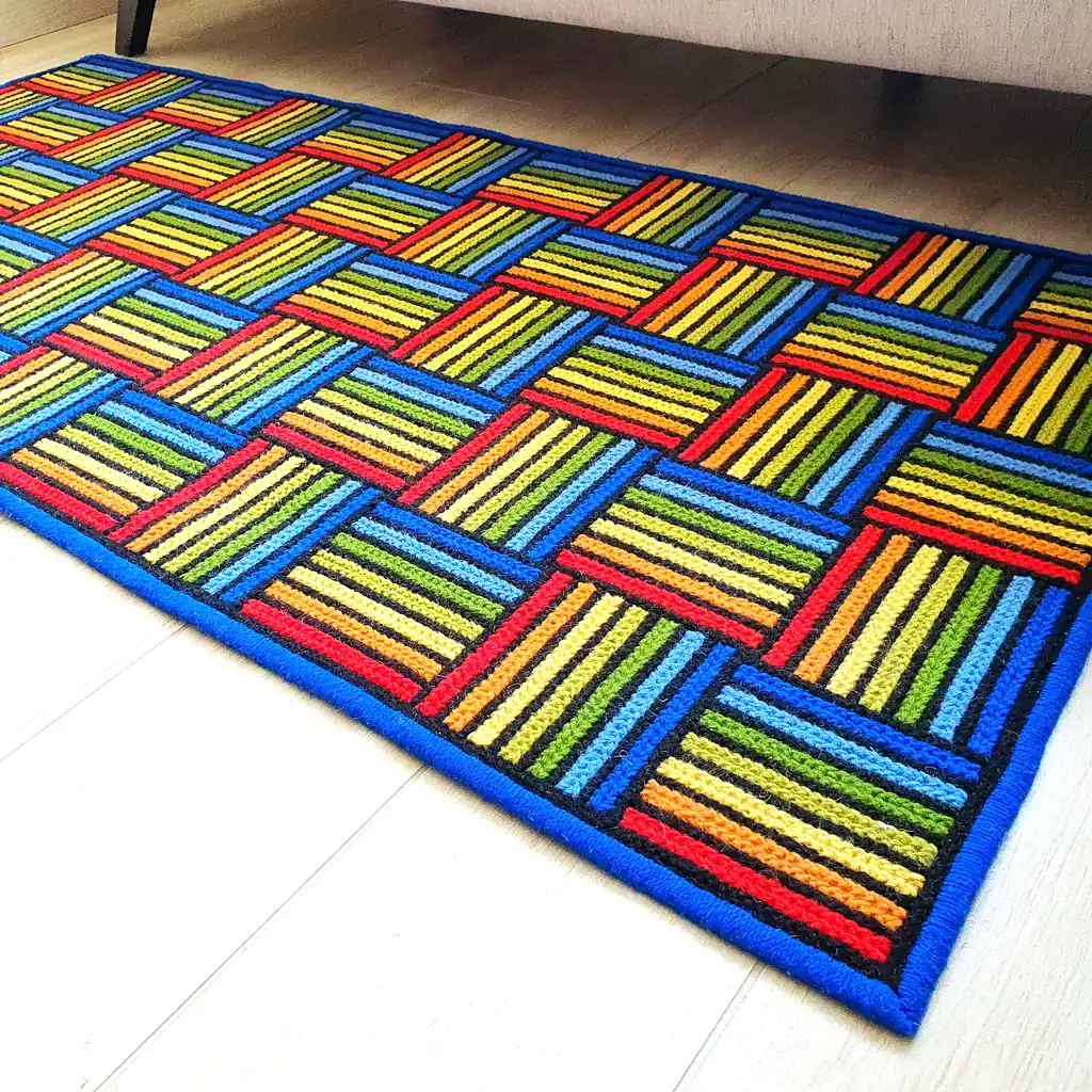 Hand-stitched textile art floor mat with saturated yellow, orange, and blue hues.
