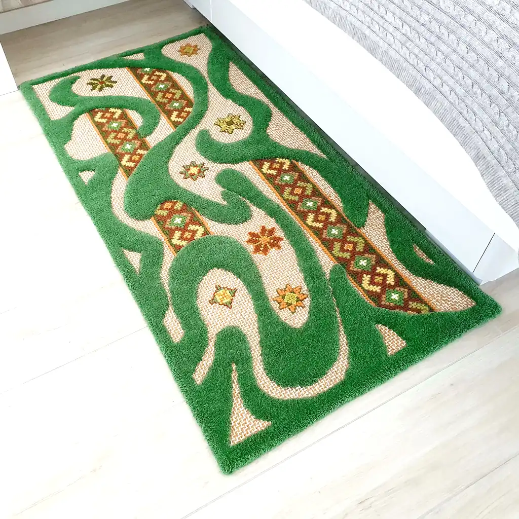 A green textured rug placed by a white bed, showing its size and scale.