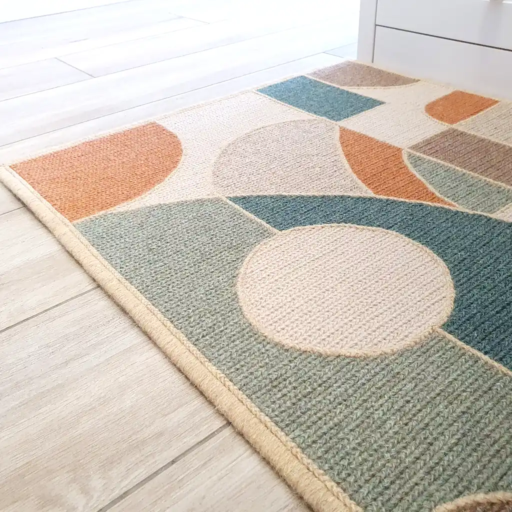 Handmade embroidered wool rug with geometric mosaic pattern in teal, orange, and cream colors with thick plush lining and natural jute border