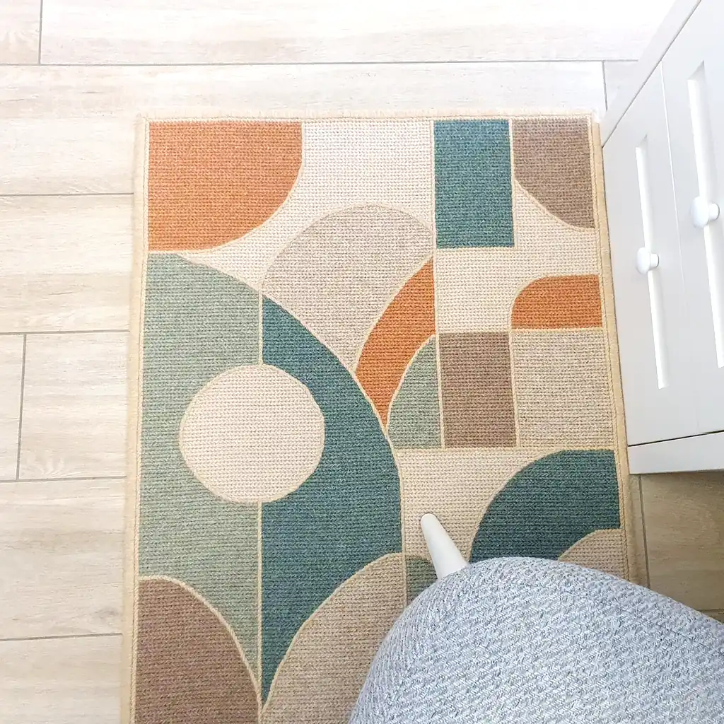 Handmade embroidered wool rug with geometric mosaic pattern in teal, orange, and cream colors with thick plush lining and natural jute border