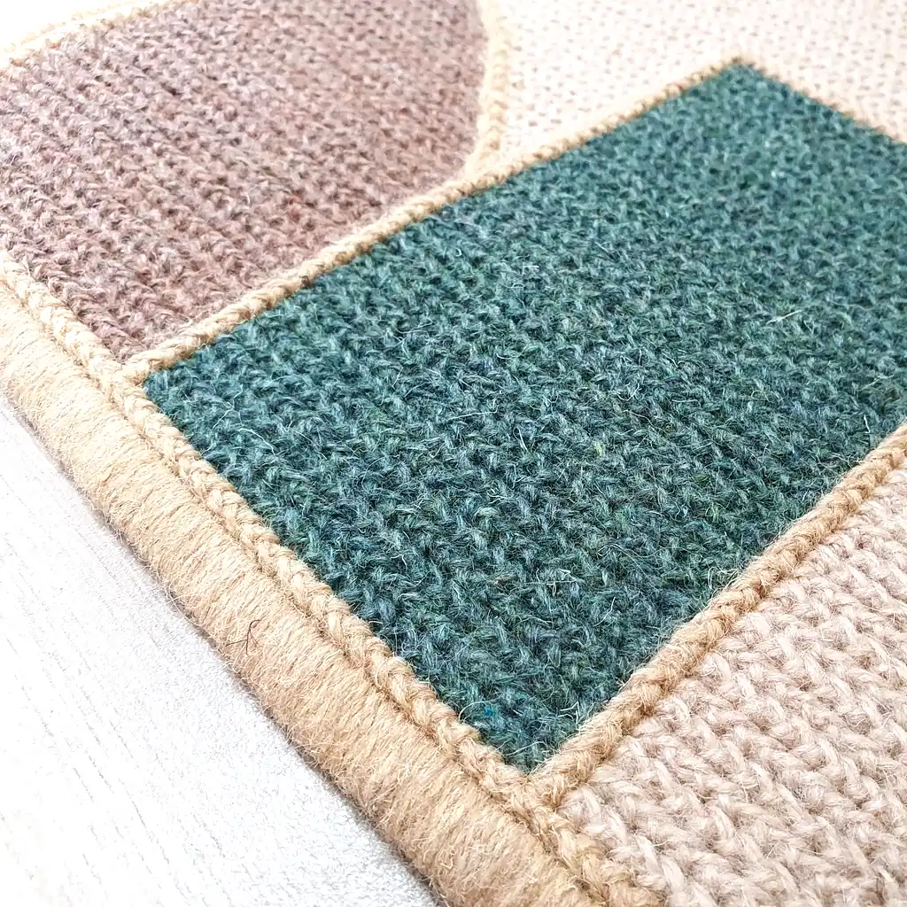 Handmade embroidered wool rug with geometric mosaic pattern in teal, orange, and cream colors with thick plush lining and natural jute border