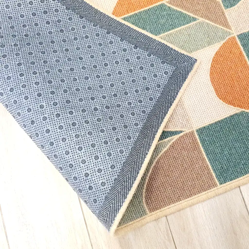 Handmade embroidered wool rug with geometric mosaic pattern in teal, orange, and cream colors with thick plush lining and natural jute border