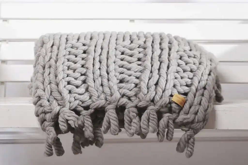 chunky wool knitted blanket in neutral tones, handcrafted textile home decor.