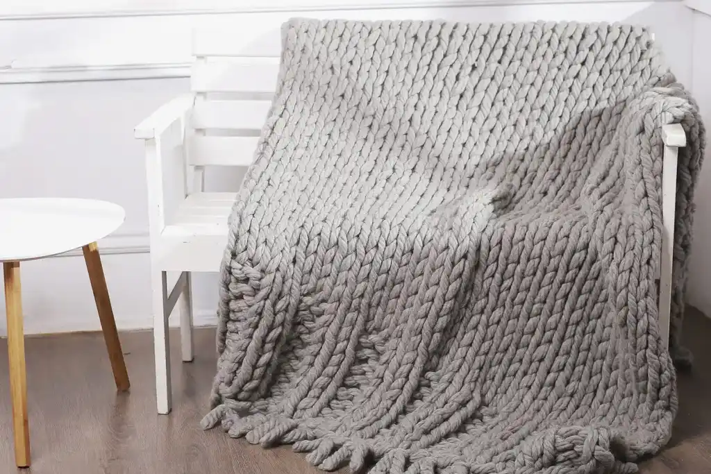 chunky wool knitted blanket in neutral tones, handcrafted textile home decor.