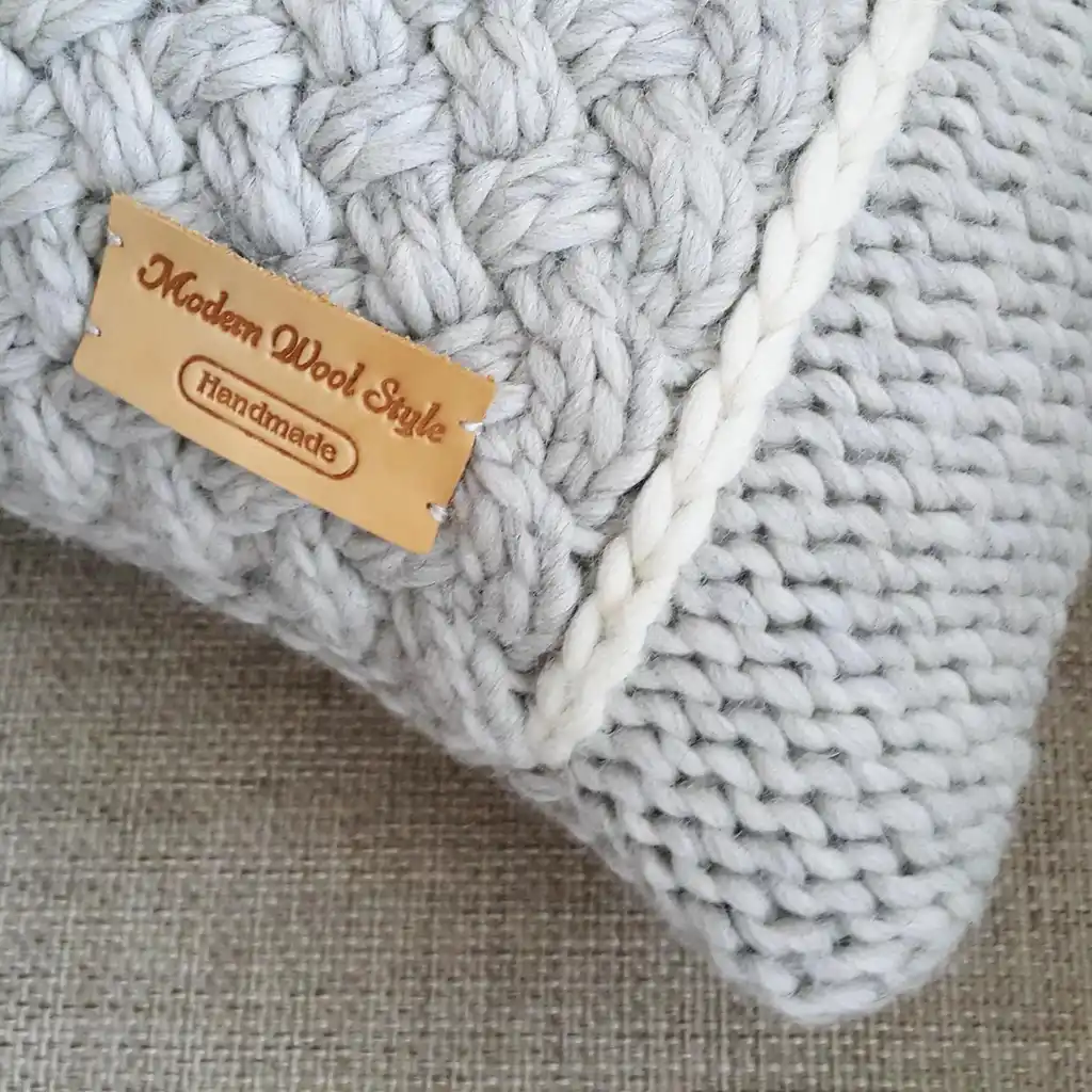 Handmade merino wool knitted cushion with textured pattern in gray color.