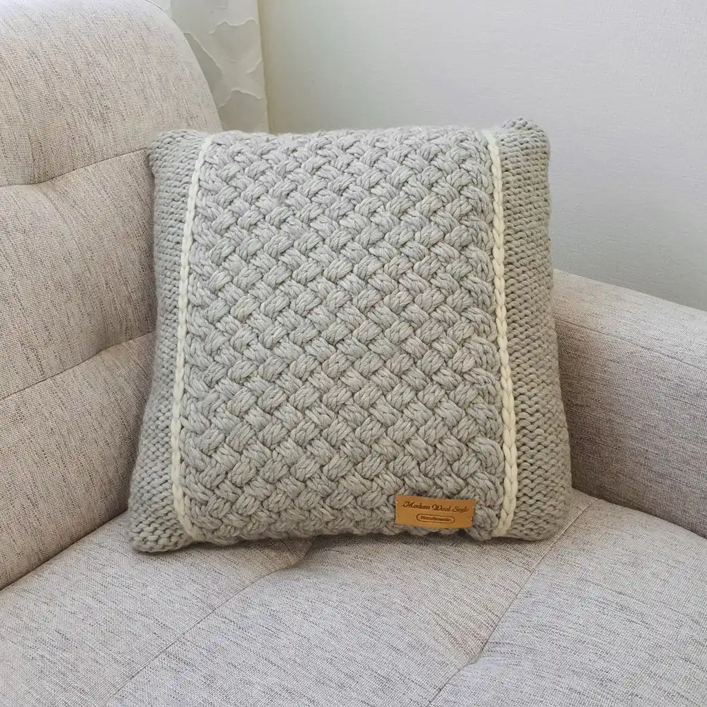 Handmade merino wool knitted cushion with textured pattern in gray color.
