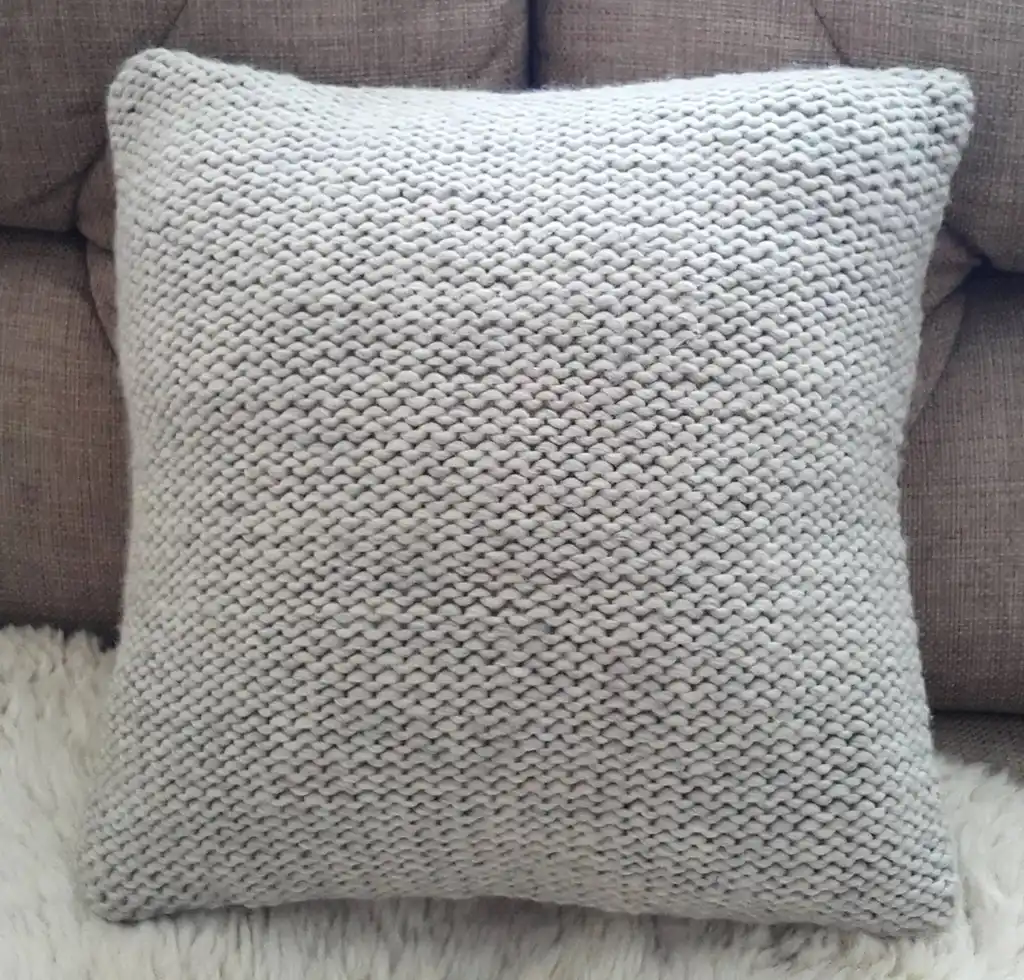 Handmade merino wool knitted cushion with textured pattern in gray color.