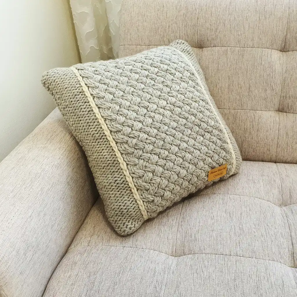 Handmade merino wool knitted cushion with textured pattern in gray color.
