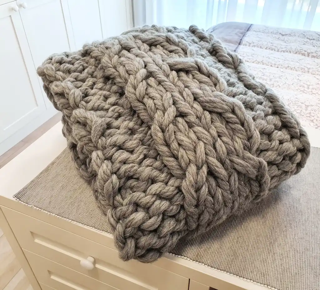 chunky wool knitted blanket in neutral color, handcrafted cozy throw for home comfort.