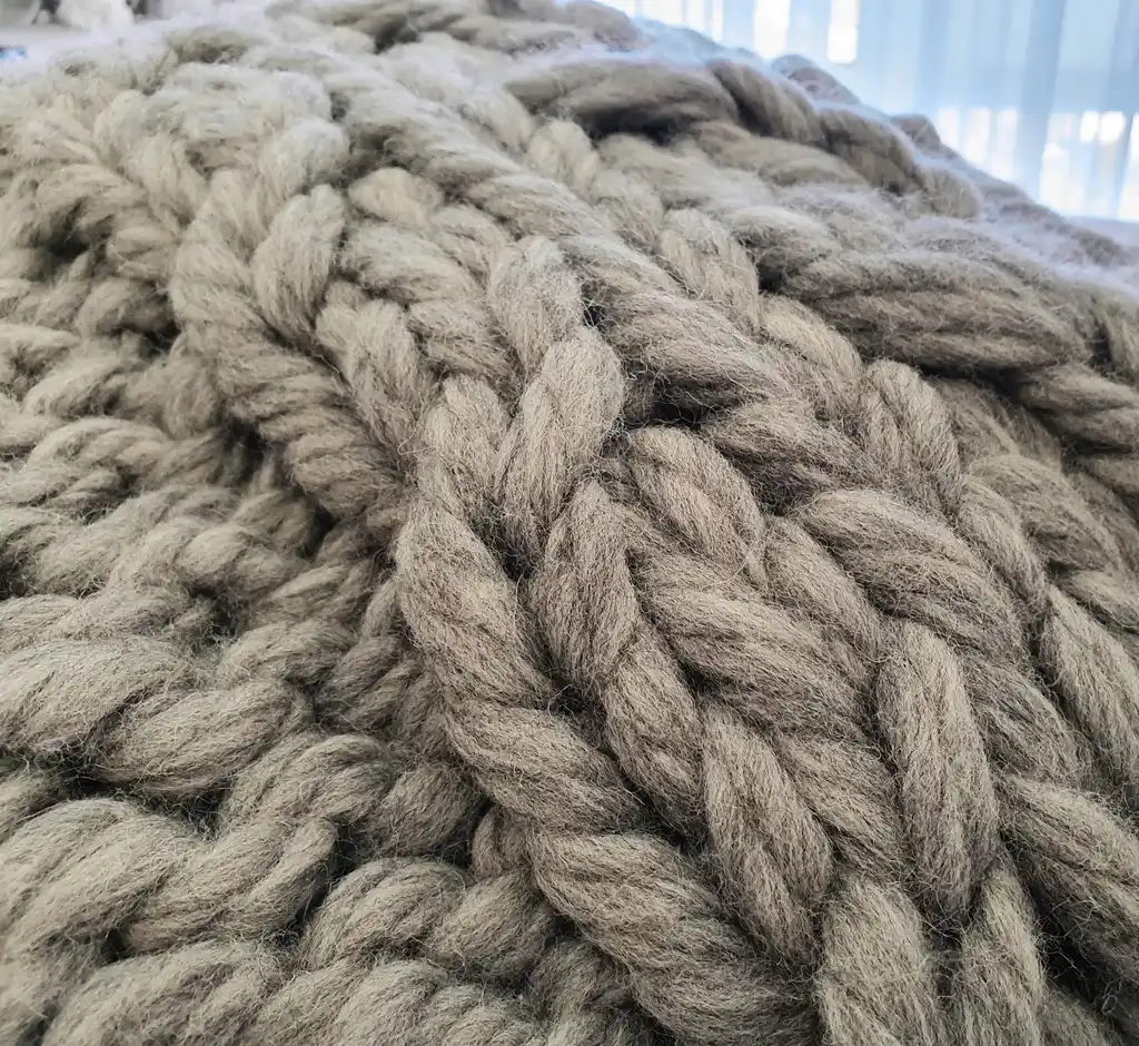 chunky wool knitted blanket in neutral color, handcrafted cozy throw for home comfort.