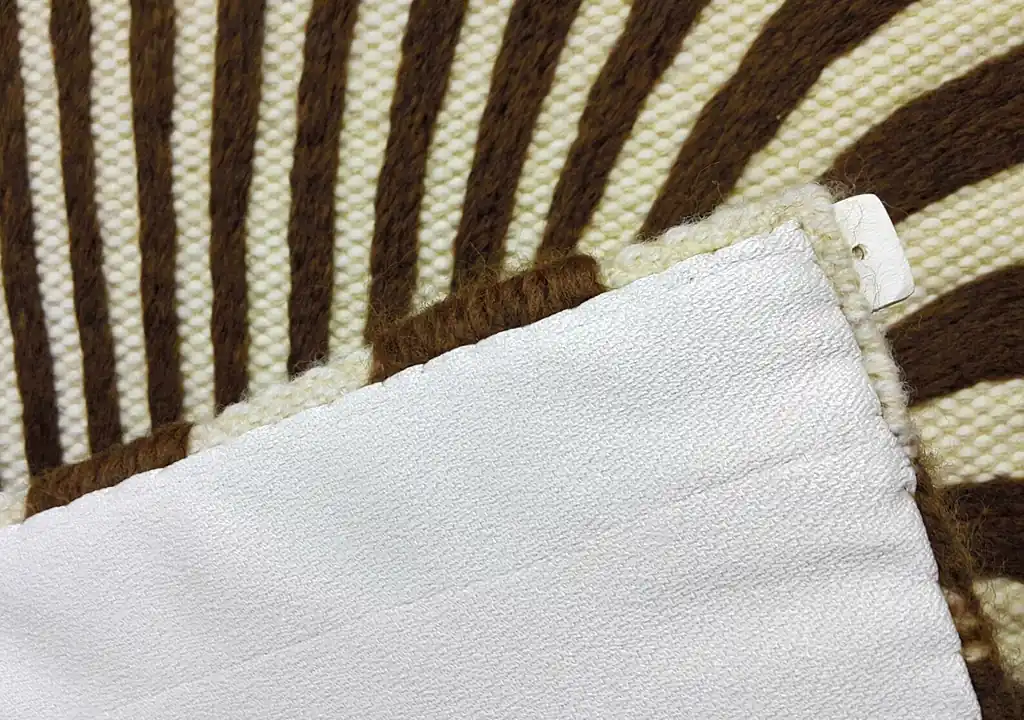 Handmade knitted wool wall hanging with radiating brown and beige fountain pattern creating optical depth effect