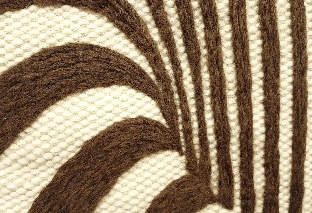 Handmade knitted wool wall hanging with radiating brown and beige fountain pattern creating optical depth effect