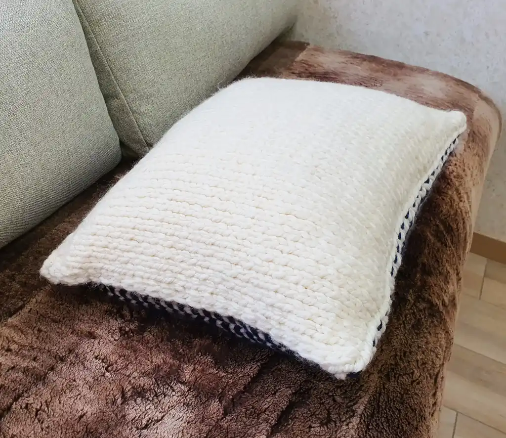 Crochet wool cushion in neutral tones, decorative home accent piece.