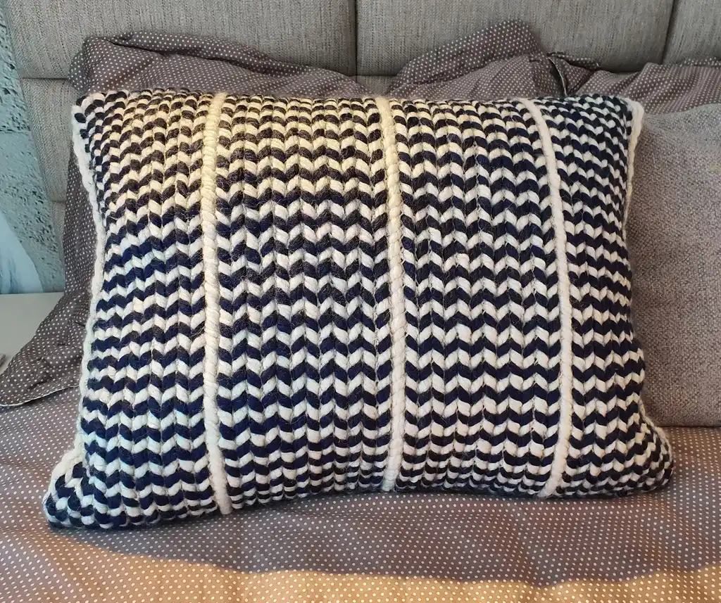 Crochet wool cushion in neutral tones, decorative home accent piece.